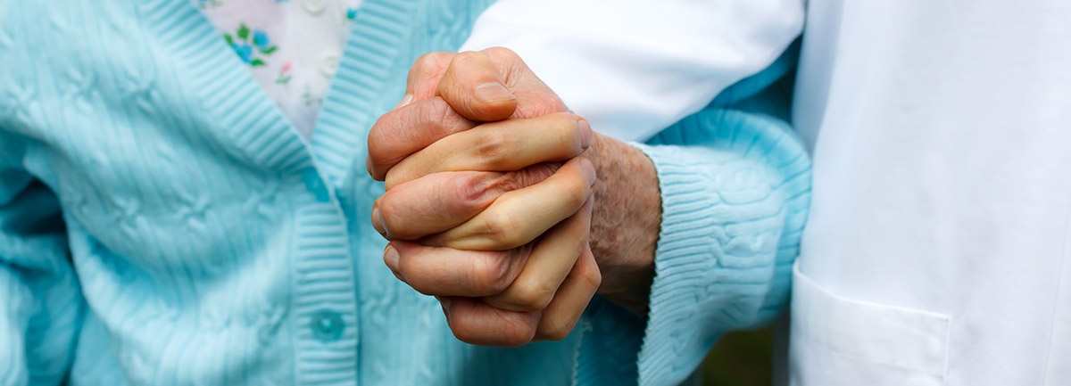 Older woman holding hands with doctor
